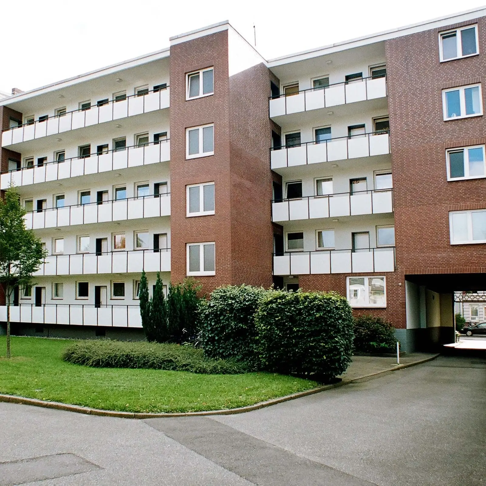 Mehrfamilienhaus aus Ziegelstein mit Bäumen.